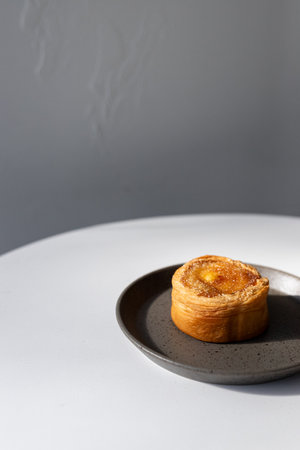 Egg tart with raisins on a black plate on a gray backgroundの写真素材