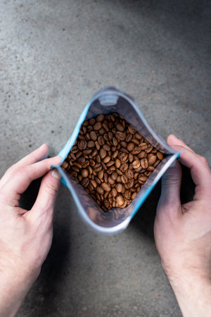 Coffee beans in a plastic container in the hands of a man