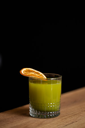 Cocktail with orange on a wooden table against a black backgroundの写真素材