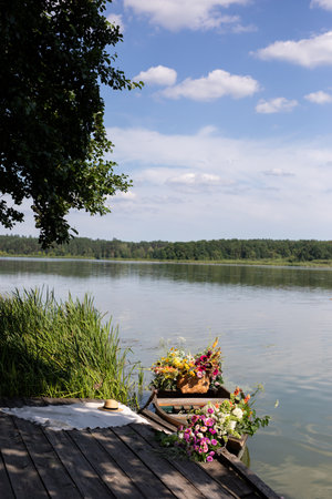 Beautiful summer landscape with a lake, trees and flowers in a vaseの写真素材
