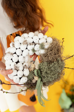 cropped shot of woman holding easter basket with eggs on yellow backgroundの写真素材