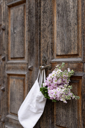 Wedding bouquet of pink flowers hanging on old wooden doorの写真素材