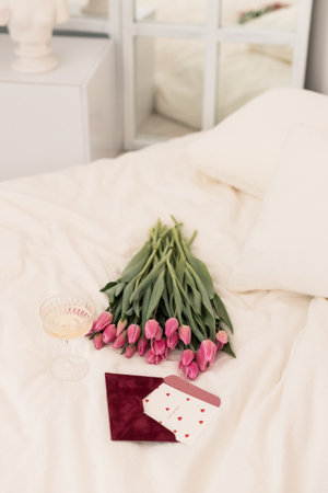 Bouquet of pink tulips and gift box on the bedの写真素材