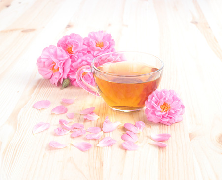 Delicious rose tea with roses on wood.の写真素材