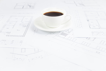 Architectural office desk with blueprints and coffe cup の写真素材