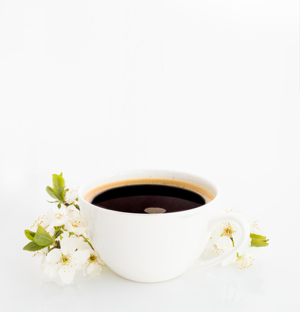 Cup of coffee with branches of blooming cherry on white background.の写真素材