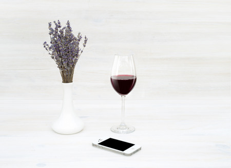 SEVASTOPOL, UKRAINE - MAY 7, 2015: An iPhone 4S smartphone photographed on a wooden table with glass of wine  and bouquet of lavender.のeditorial素材