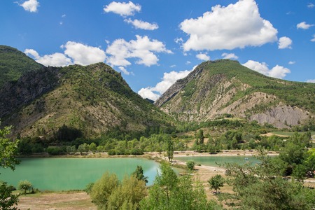 Mountain lake located through the green forest in the french Alps.の写真素材