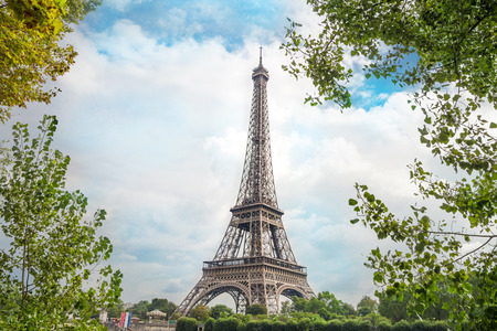 View on Eiffel tower through green trees with cloud bckground. Eiffel Tower from Champ de Mars, Paris, France.の写真素材