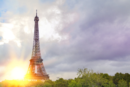 View on Eiffel tower over green summer trees with sunset rays. Beautiful Romantic background. Eiffel Tower from Champ de Mars, Paris, France.の写真素材