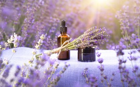 Essential lavender oil in the bottle with dropper on the table in lavender field. Horizontal close-up.の写真素材
