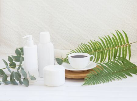 Spa composition of Jar of cream and shampoo bottle with black coffee cup on bamboo plate over decorationの写真素材