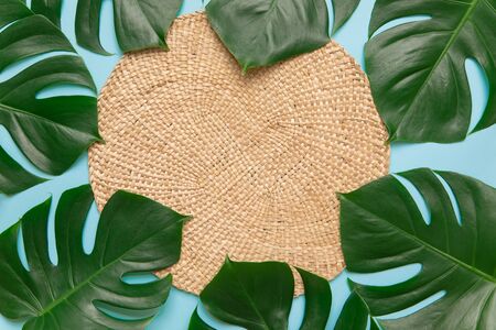 Round wicker stand and palm leaves on blueの写真素材