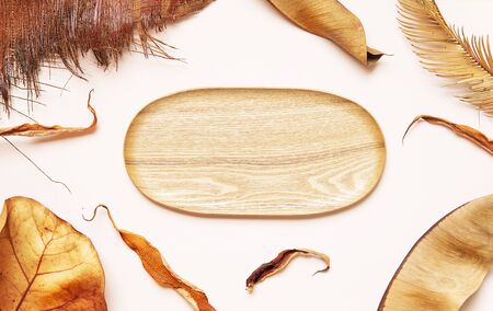 Light background with natural materials and empty wooden plate, with tropical leaves and eucalyptus. Top view with copy space.の写真素材