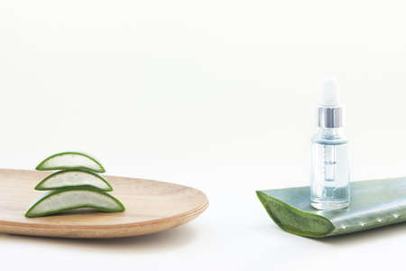 Essence bottle and aloe vera leaves on a white background.の写真素材