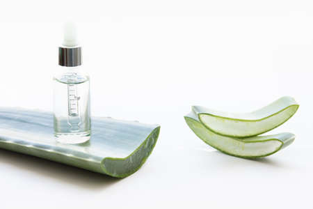 Essence bottle and aloe vera leaves on a white background.の写真素材