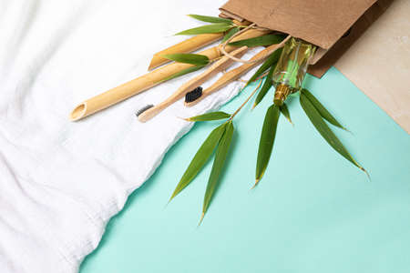Bamboo toothbrush and eco bag on a table with copy space on a blue background. Styled composition of flat lay with bamboo leaves .の写真素材