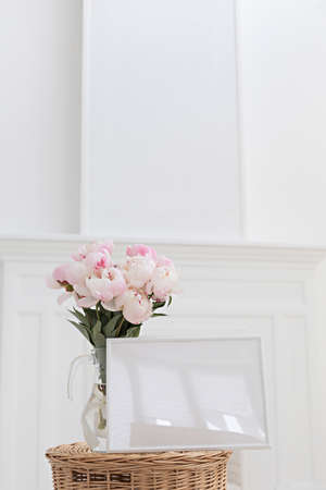 Horisontal frame mockup. Glass vase with a bouquet of pink peonies. Modern fireplace in a Scandinavian interior.の写真素材