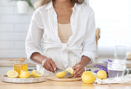 Preparation of fresh lavender lemonade. Step 3, ingredients for a making summer fresh cocktail. Users guide. The girl makes a drink and cuts lemons in the kitchen.の写真素材