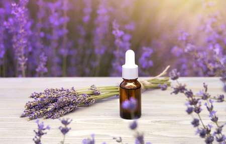 Essential lavender oil in the bottle with dropper on the gray wooden desk. Horizontal close-up.の写真素材
