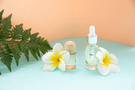 A bottle of essential oils and tropical flower on a pastel background. Skin and body care concept.の写真素材