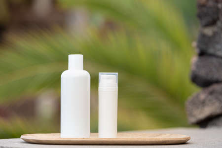 Skin care concept with white bottle and palm leaves on tropical background.