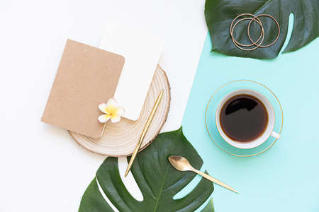 Tropical workspace concept. Notepad and tropical palm leaves. Mockup presentation workplace.の写真素材