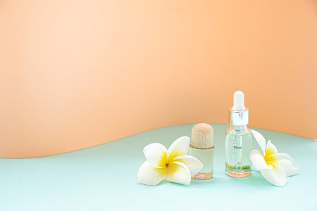 A bottle of essential oils and tropical flower on a white background. Skin and body care concept.の写真素材