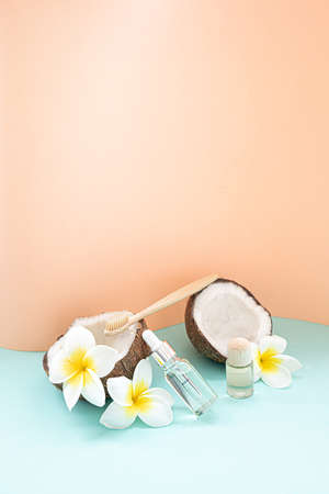 Bamboo toothbrush and bootle essential oil on a table with copy space on a white background. Styled composition of flat lay with tropical leaves and flowers.の写真素材