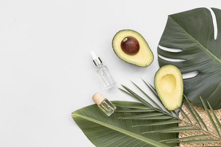 Bottle essential oils and avocado on tropical background. Skin and body care treatment concept.の写真素材