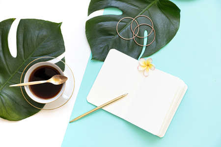 Tropical workspace concept. Notepad and tropical palm leaves. Mockup presentation workplace.の写真素材