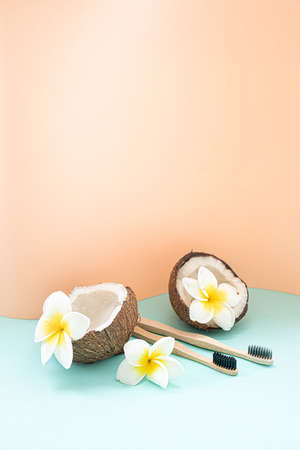 Bamboo toothbrush and coconut on a table with copy space on a pastel background. Styled composition of flat lay with tropical flowers.の写真素材