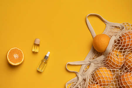 Fresh oranges in a eco bag. Cutted citrus fruit for healthly food. A bottle of essential oils.の写真素材