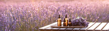 Essential lavender oil in the bottle with dropper on the gray wooden desk. Horizontal close-up.の写真素材