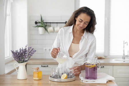A young girl makes lemonade from lemons and lavender. Woman making a summer drink.の写真素材