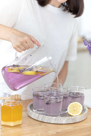 A young girl makes lemonade from lemons and lavender. Woman making a summer drink.の写真素材