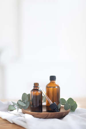 Essential oils in glass dark bottle. Skin and body care treatment concept. Eucalyptus branch.の写真素材