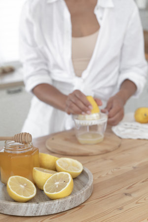 Preparation of fresh llemonade. Young girl squeezes lemon juice in the kitchen near the windowの写真素材