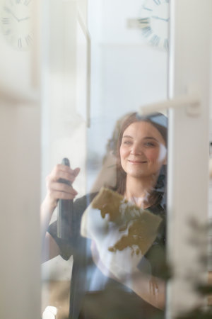 Woman cleaning window at home with rag and spray.の写真素材