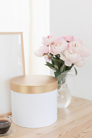 Vertical frame and gift box mockup on a wooden table in the kitchen. Glass jug with a bouquet of...