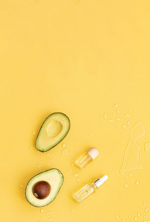 Bottle essential oils and avocado on tropical background. Skin and body care treatment concept.の写真素材