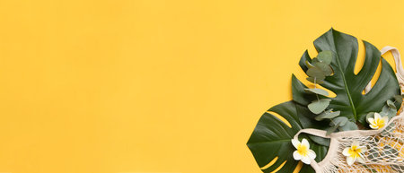 Tropical palm tree leaf and hat on a yellow background. The place is empty on the photo for your text. Vibrant minimal fashion conceptの写真素材