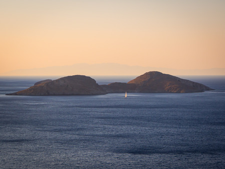 Sailing boat at sunset near Tilos island, Greeceの写真素材