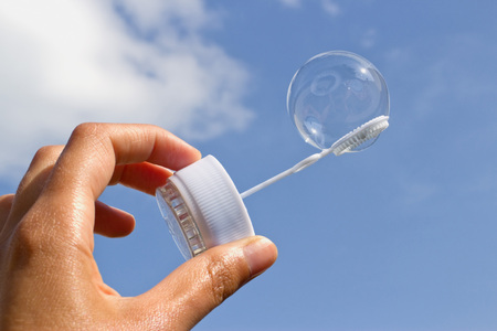 WomansÂ´s hand is holding bubble blower with one beautiful bubbleの写真素材