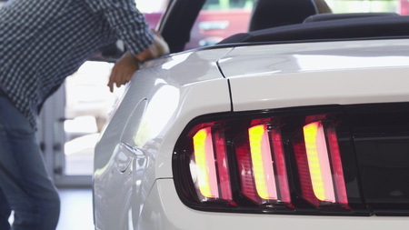 Selective focus on car lights flashing while male customer opening car door for his girlfriend....