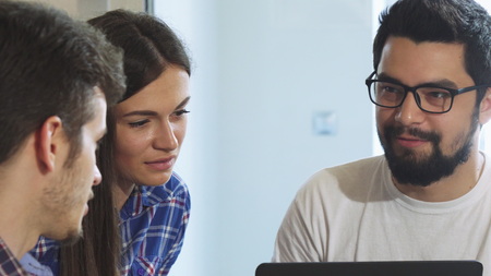Sliding close up shot of a group of young people talking at the cafe. Young cheerful friends enjoying their leisure time, relaxing together. Friendship, diversity, communication.の写真素材