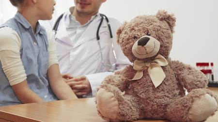 In the foreground on the table is a teddy bear. He has a nice bow on his neck. In the background sit...