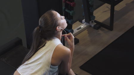 Top view shot of a happy young beautiful sporty woman listening to music smiling to the camera over...