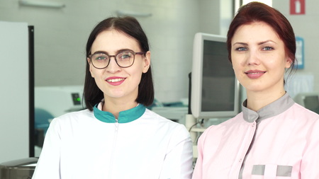 Shot of two female colleagues professional biologists smiling to the camera posing proudly at the laboratory. Medical staff. Modern laboratory researchers team. Emancipation concept.の写真素材