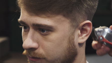Sliding cropped close up of a young man getting a new haircut at the barbershop professional barber...